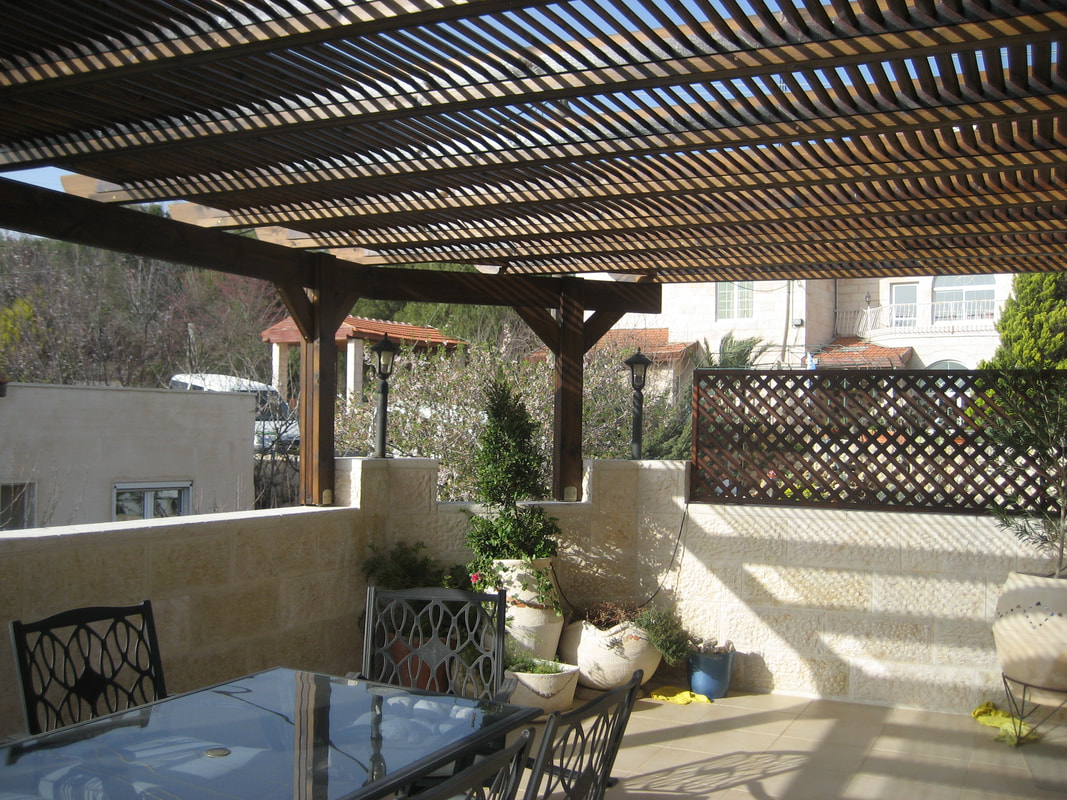 Dark stained pergola with sechach slats in the Gush
